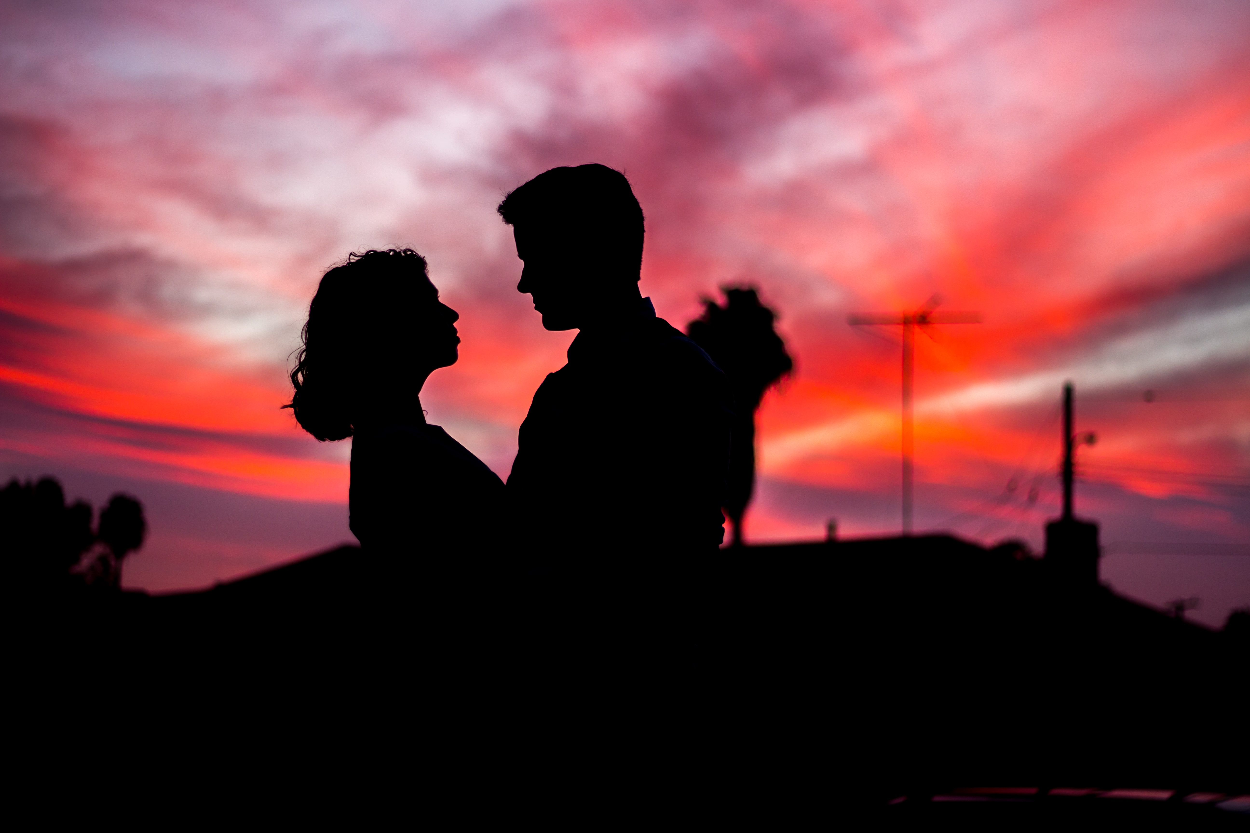 Man and woman standing in front of a sunset.