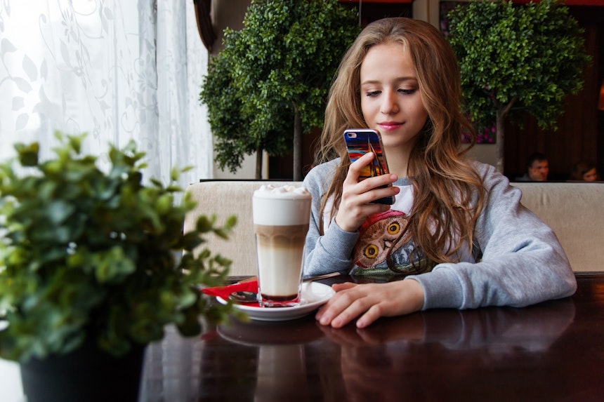 Girl on phone while drinking coffee.
