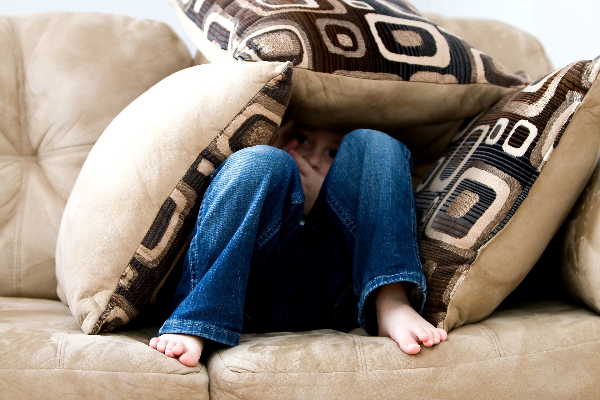 Child hiding under cushions.